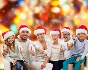 Image showing happy family in santa hats showing thumbs up