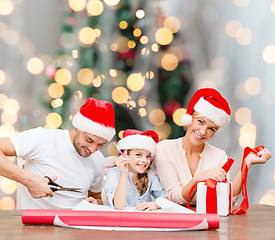 Image showing happy family in santa helper hats packing gift