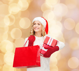 Image showing smiling young woman in santa helper hat with gifts