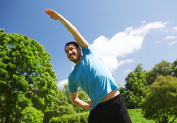 Image showing smiling man stretching outdoors