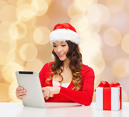 Image showing smiling woman in santa hat with gift and tablet pc