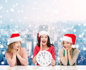 Image showing smiling women in santa helper hat with clock