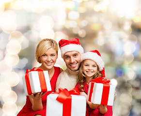 Image showing happy family in santa helper hats with gift boxes