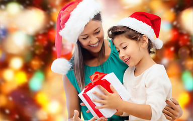 Image showing happy mother and girl in santa hats with gift box