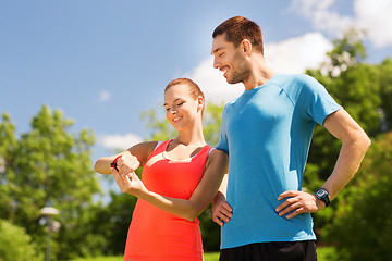 Image showing smiling people with heart rate watches outdoors