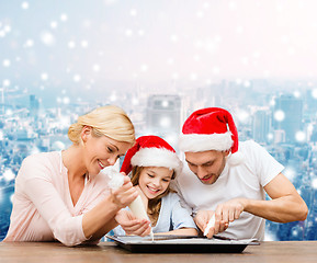 Image showing happy family in santa helper hats cooking