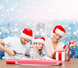 Image showing happy family in santa helper hats packing gift