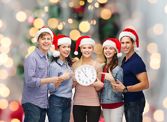 Image showing group of teenagers in santa helper hats with clock