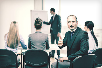 Image showing businessman with team showing thumbs up in office