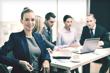 Image showing businesswoman with glasses with team on the back