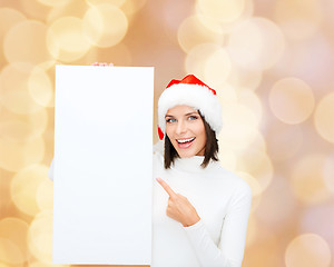 Image showing smiling young woman in santa hat with white board