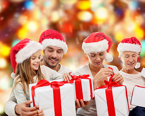 Image showing happy family in santa helper hats with gift boxes