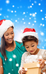 Image showing happy mother and girl in santa hats with gift box