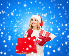 Image showing smiling young woman in santa helper hat with gifts