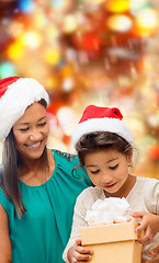 Image showing happy mother and girl in santa hats with gift box