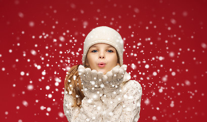 Image showing happy girl in winter clothes blowing on palms