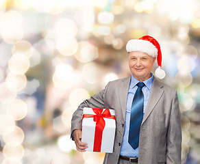 Image showing smiling man in suit and santa helper hat with gift