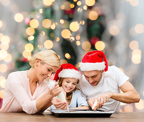 Image showing happy family in santa helper hats cooking