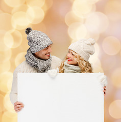 Image showing smiling couple in winter clothes with white board