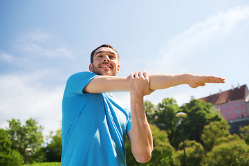 Image showing smiling man stretching outdoors