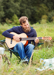 Image showing smiling man with guitar and dixie in camping