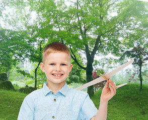 Image showing smiling little boy holding a wooden airplane model