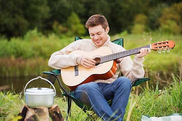 Image showing smiling man with guitar and dixie in camping