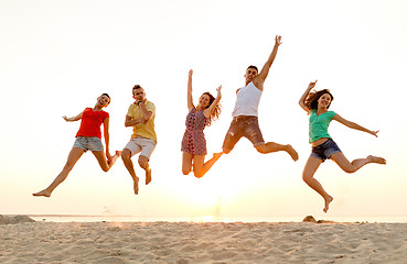 Image showing smiling friends dancing and jumping on beach