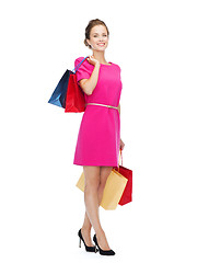 Image showing smiling woman in pink dress with shopping bags