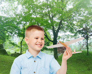 Image showing smiling little boy holding a wooden airplane model