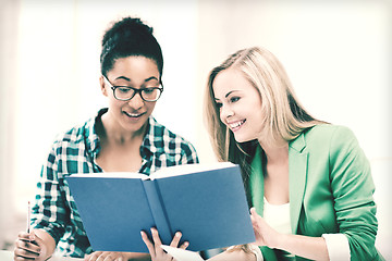 Image showing smiling student girls reading book at school