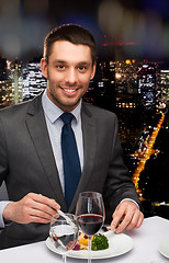 Image showing smiling man eating main course