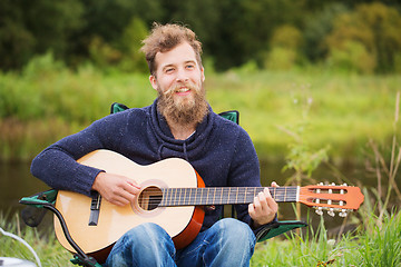 Image showing smiling man playing guitar in camping