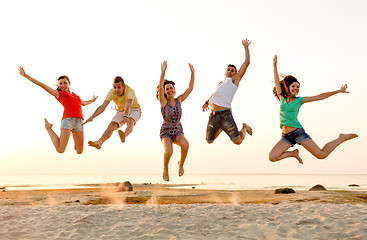 Image showing smiling friends dancing and jumping on beach