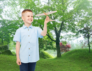 Image showing smiling little boy holding a wooden airplane model