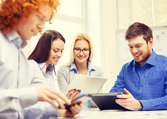 Image showing smiling team with table pc and papers working