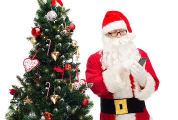 Image showing santa claus with smartphone and christmas tree