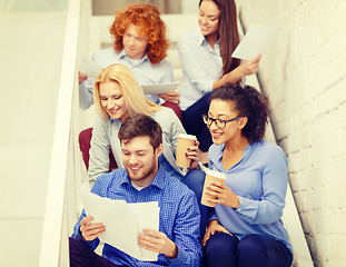 Image showing team with papers and take away coffee on staircase