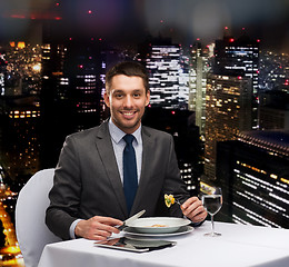 Image showing smiling man with tablet pc eating main course