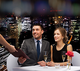 Image showing waiter giving menu to happy couple at restaurant