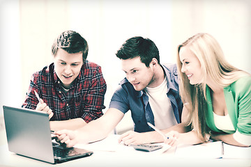 Image showing smiling students looking at laptop at school