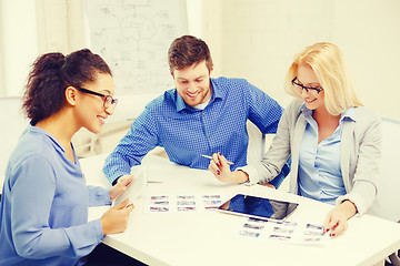 Image showing smiling team with table pc and papers working