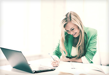 Image showing smiling student girl writing in notebook