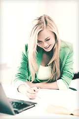 Image showing smiling student girl writing in notebook