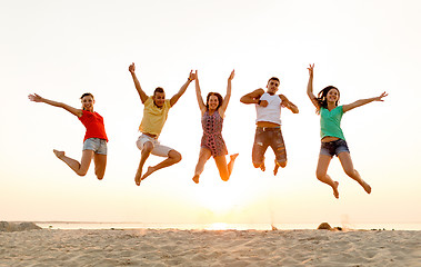 Image showing smiling friends dancing and jumping on beach