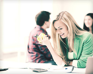 Image showing smiling student girl eating apple at school