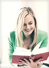 Image showing smiling young woman reading book at school