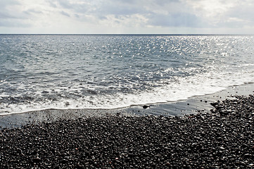 Image showing Black pebbles and sea