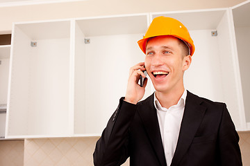 Image showing smiling engineer talking on the phone in the interior 