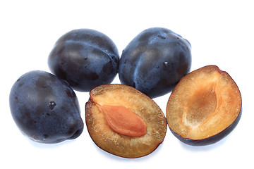 Image showing Three plums and one halved